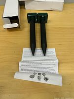 Two repeller stakes, instruction sheet and open box visible