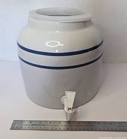 Full view of ceramic crock showing bands and spigot with ruler for scale