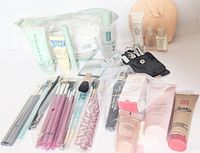 Full lot overview showing brushes, skincare tubes, pouches, Clinique bottle, clear zip bag