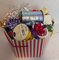 Striped bag filled with various ribbon spools and bows