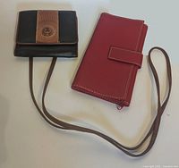 Both wallets front view showing colors, straps and size comparison