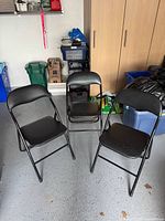 Three black folding chairs opened and standing