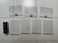 Seven clear acrylic frames arranged with a beverage can for scale