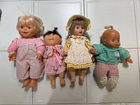 Group of four baby dolls with differing outfits and hairstyles