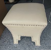 Full view of cream square stool with nailhead trim
