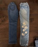 Both pairs of jeans laid flat showing full length and styles