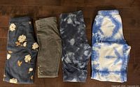 Four pairs of pants laid flat side-by-side showing patterns and colors