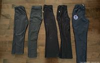 Five pairs girls pants laid flat side by side