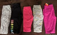 Five pairs leggings laid flat showing full length and patterns