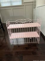 Front view of pink metal two-tier shelf stand