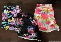 Three pairs of girls shorts laid out flat showing patterns and condition