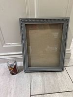 Front view of grey shadow box beside soda can