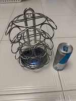 Front view of chrome rotating Keurig pod holder beside standard 250 ml can for scale