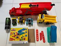 Top-down view of Play-Doh kit, car carrier, dump truck, three small vehicles and Play-Doh accessories