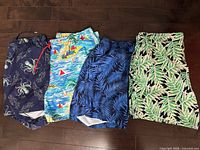Four pairs of patterned Lands’ End swim trunks displayed on floor