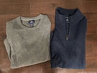 Grey and navy sweaters folded on floor