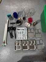 Overview of kitchen items on floor including utensils, containers, lunch trays and rods