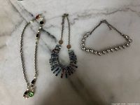 Three necklaces laid out showing design and colours
