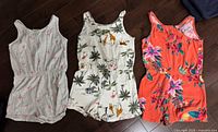 Front view of three rompers laid flat showing prints and style