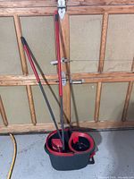 Bucket and two mop handles leaning against garage door