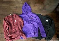 Three sweatshirts laid flat showing front designs and condition