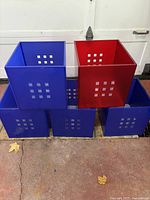 Front view of five Ikea Kallax storage boxes, four blue and one red, showing perforated square cut-outs