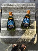 Two sealed Crest Pro-Health Intense mouthwash bottles placed on striped bath rug