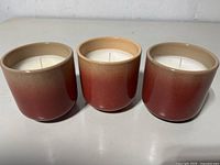 Front view of three gradient red-beige ceramic jar candles