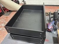 two stacked brown Ikea under-bed drawers on casters