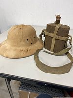 Pith helmet and canteen side by side on table