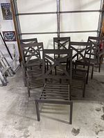 Six brown aluminum chairs stacked in garage