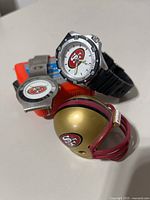 Group shot of two watches and mini helmet