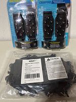 Front view of two packaged traction cleats and sealed Ninat crampons bag