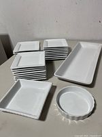 Stacks of white square plates, rectangular platter, square and round serving dishes