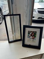 Two black picture frames on windowsill, one narrow and one medium with stock photo