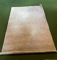 Top view of beige carpet remnant showing bound edge and overall texture