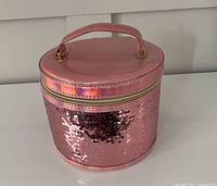 Front view of cylindrical pink makeup case with sequins and handle