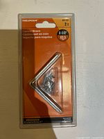 Front of sealed Hillman Corner Brace 2-1/2 in package showing contents