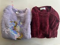 Front view of both sweaters folded side by side