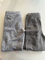 Both pairs of sweatpants folded side-by-side showing fabric colour and texture