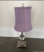 Front view of purple table lamp showing shade, base, glass orb accent, finial, and cord