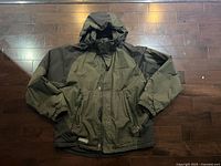 Front view of green and dark olive Expeditions winter jacket showing hood, zipper, pockets
