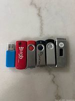 Six USB flash drives lined up showing colors, styles, and 32GB marking on one