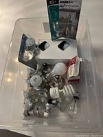 Plastic bin filled with assorted light bulbs showing various types and packaging