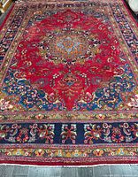 Full view of handmade Mashhad rug showing red field and floral borders