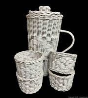 White wicker pitcher with lid and four matching cup holders displayed upright