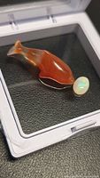 Side view of carnelian dolphin with opal cabochon attached