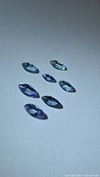 Seven marquise-cut tanzanite stones arranged on neutral background