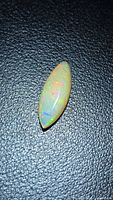 Marquise cabochon opal on black background, showing play of color