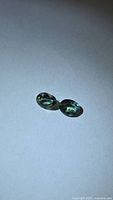 Pair of oval blue-green sapphires on neutral background